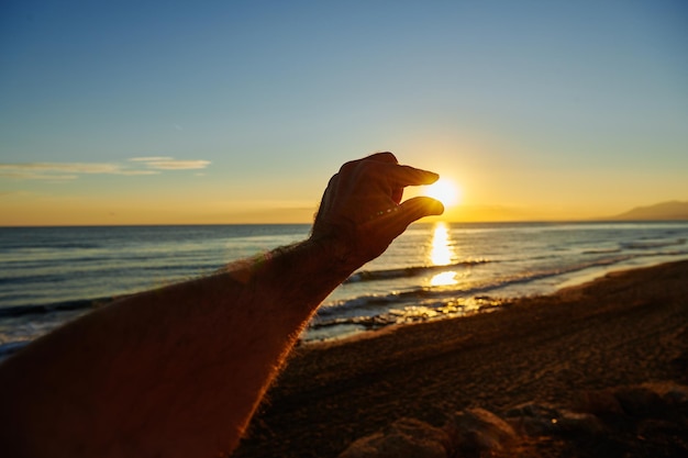 UMA MÃO PEGANDO O SOL COM AS MÃOS