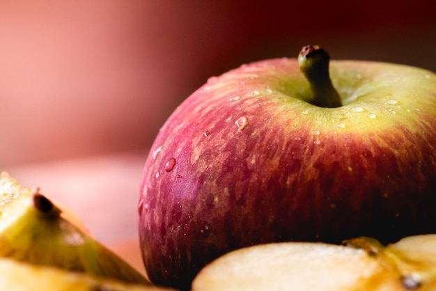 Uma maçã em macro fotografia com algumas gotas de água com pedaços de maçã na composição