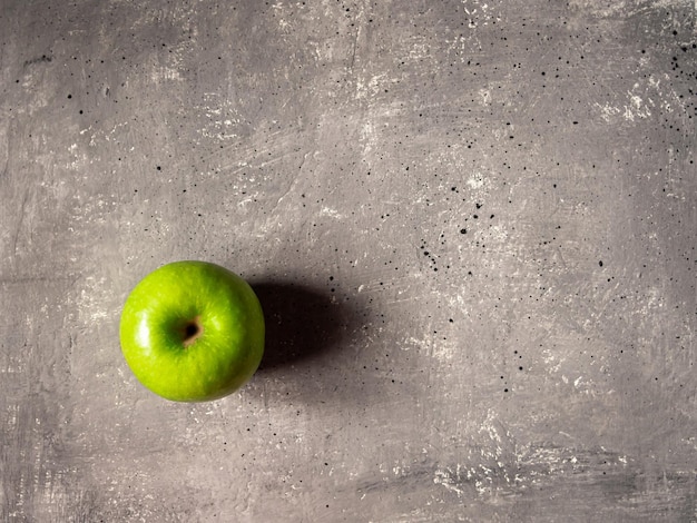 Uma maçã verde em um fundo cinza de concreto