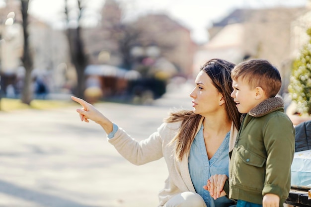 Uma mãe apontando para algo em um parque e conversando com o filho