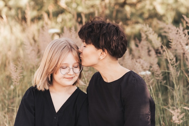 Uma mãe beija sua filha adolescente na natureza no verão