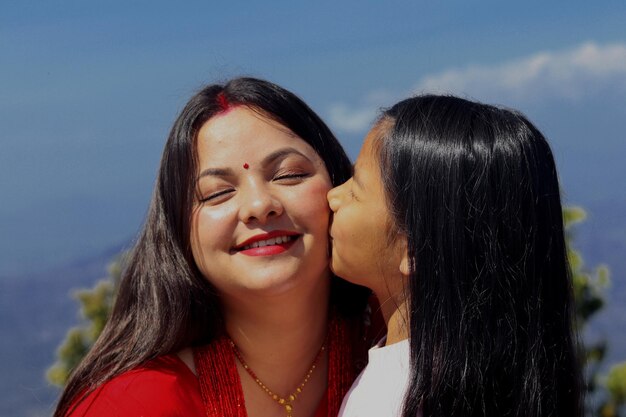 Uma mãe beijando sua filha em um dia ensolarado