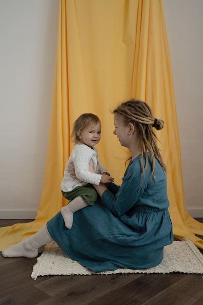 Uma mãe com dreadlocks e uma criança sentam no tapete e passam tempo juntos Dia das mães