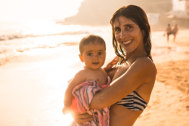 Foto uma mãe com seu bebê apreciando o pôr do sol em uma praia, morro jable, município de pajara, ao sul de fuerteventura, nas ilhas canárias. espanha