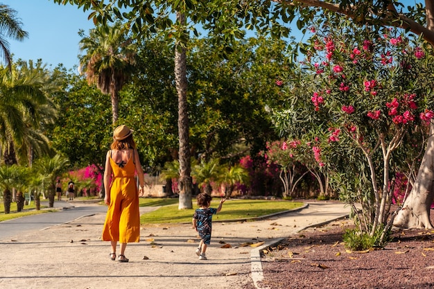 Uma mãe com seu filho de férias para os cristãos por um parque com palmeiras na ilha de Tenerife Ilhas Canárias