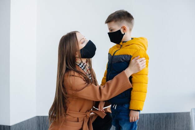 Uma mãe com seu filho fica em uma máscara durante a quarentena. Pandemia, coronavírus.