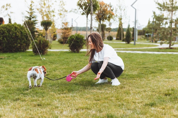 Uma mãe com um filho e um cachorro jack russell terrier estão caminhando juntos no parque uma mulher e uma garotinha estão passeando com seu cachorro