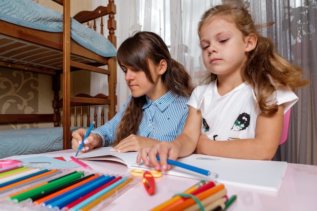 Uma mãe com um filho se senta à mesa e faz a lição de casa que a criança aprende em casa.