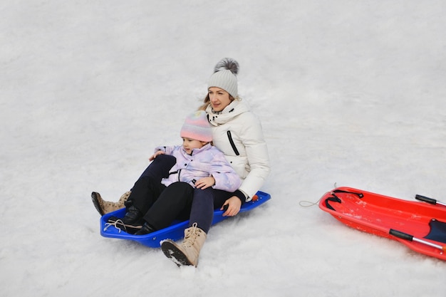 Uma mãe com uma criança andando de trenó na neve