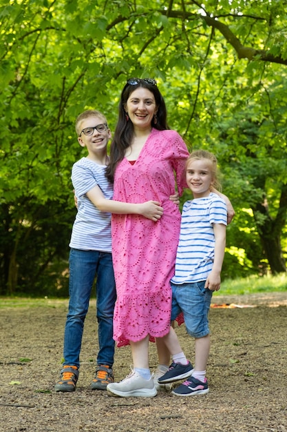 Foto uma mãe e dois filhos em idade escolar um menino e uma menina na natureza