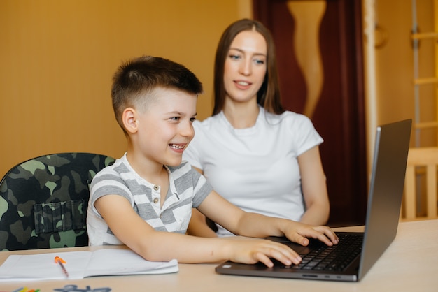 Uma mãe e seu filho estão envolvidos em ensino à distância em casa, na frente do computador. fique em casa, treinando.