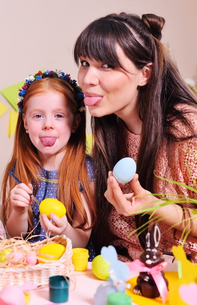 Uma mãe e sua filha estão pintando ovos.