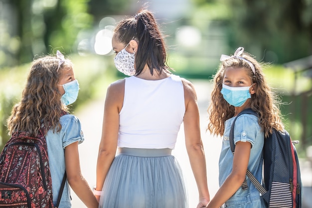 Uma mãe e sua filha gêmea usam uma máscara protetora ao retornarem à escola durante a quarentena covid-19.