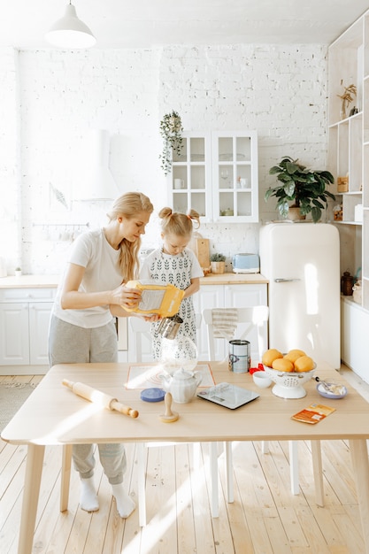 Uma mãe e sua filha pequena preparam massa de pão juntos em sua cozinha em casa.