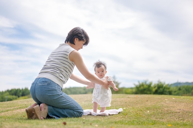 Uma mãe e um bebê estão brincando na grama.