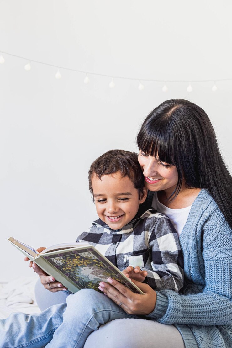 Foto uma mãe e um filho lendo um livro juntos com luzes de natal brancas atrás deles