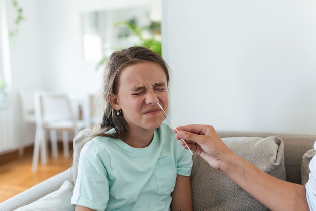 Foto uma mãe está fazendo um teste rápido de covid-19 em casa para sua filha doente em casa uma mãe está testando uma menina para infecção por coronavírus fazendo um teste acelerado de covid-19