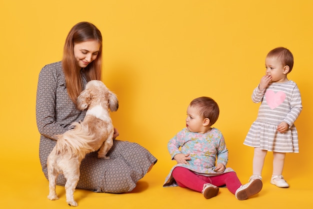 Uma mãe feliz e encantada brinca com seu animal de estimação favorito, sentada no chão, olhando para ele