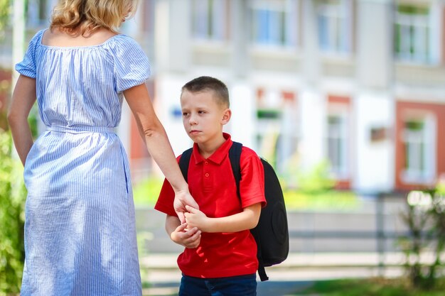 Uma mãe feliz leva a criança para a escola no caminho de volta para a escola