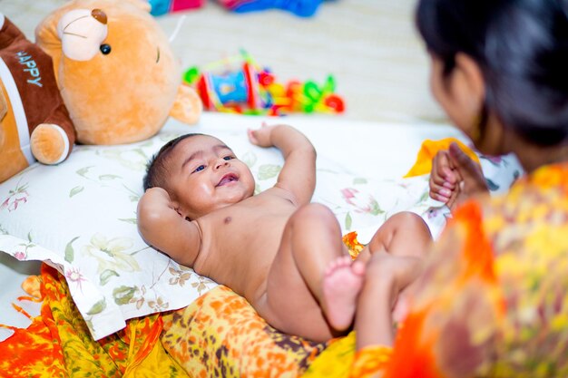 Uma mãe massageando o corpo macio de um bebê de seis meses