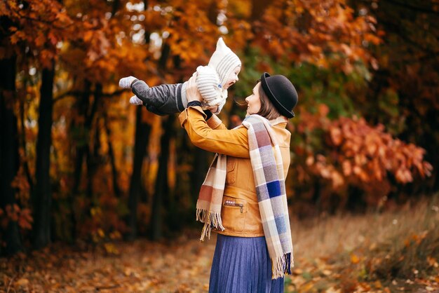 Uma mãe segura seu filho em seus braços em um parque de outono