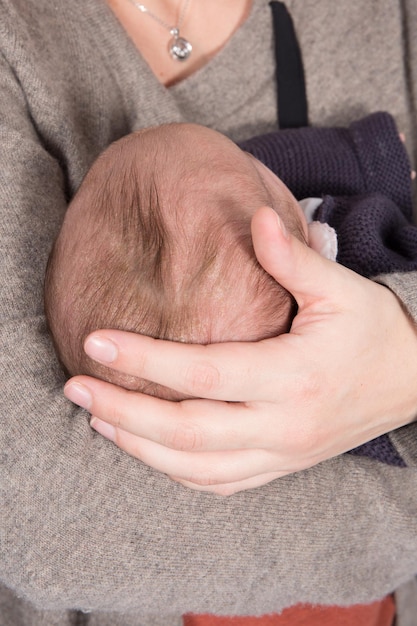 Uma mãe segurando a cabeça do bebê na mão