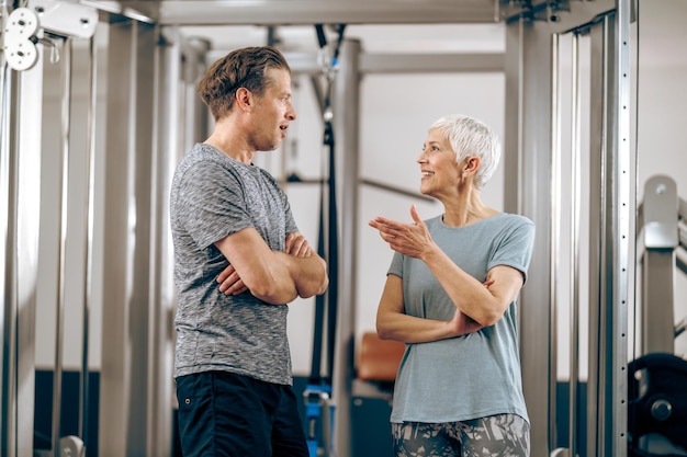 Uma mãe sênior e seu filho de meia idade conversando antes de fazer um treino em uma academia.