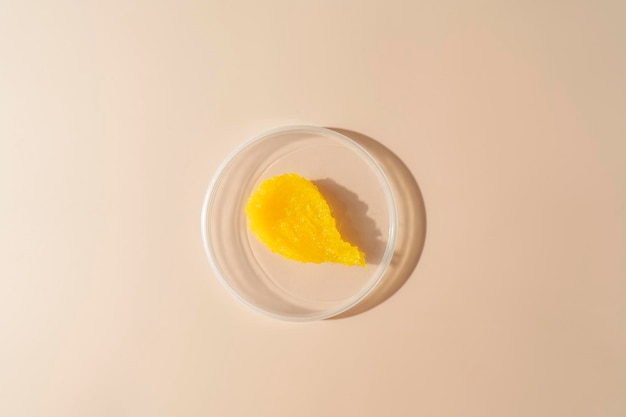 Uma mancha amarela de um esfoliante corporal de manga deitado em um prato sobre fundo bege