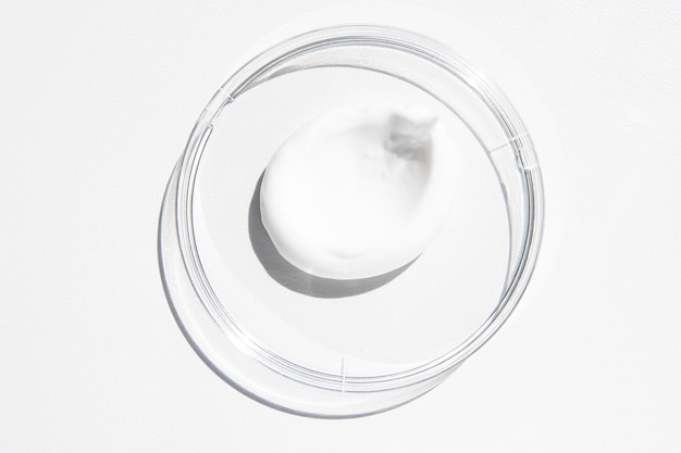 Foto uma mancha de um produto cosmético em um copo em um fundo branco com uma luz brilhante