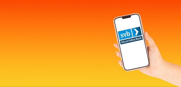 Uma mão bonita com um telemóvel com o logotipo do SVB Silicon Valley Bank no ecrã