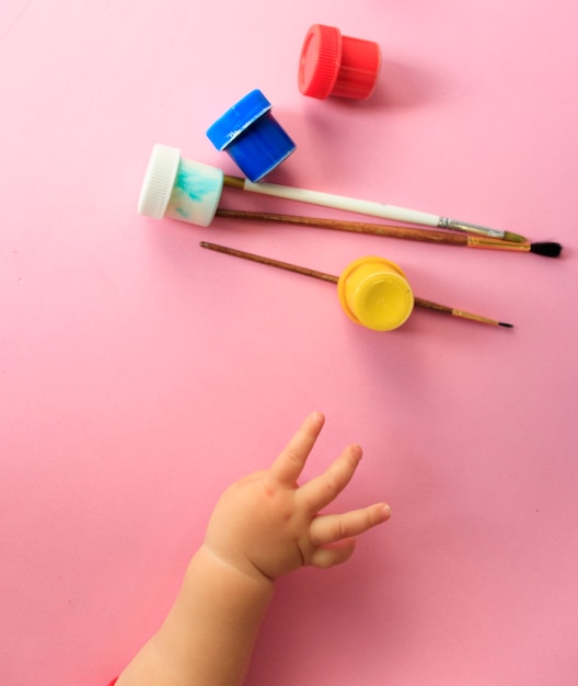 Uma mão de bebê desenhando linhas e formas com giz de cera colorido.
