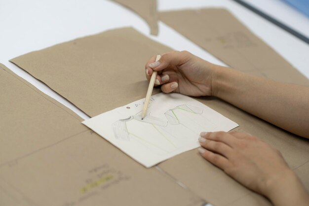 uma mão de mulher escrevendo notas no pedaço de papel em uma fábrica de costura fazendo padrões de roupas