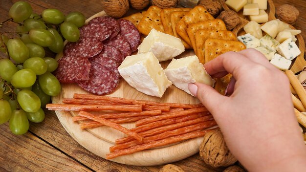 Uma mão de mulher pega um pedaço de queijo camembert de um prato de queijo