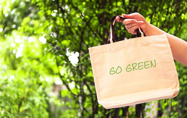 Foto uma mão de mulher segura sacola reutilizável com vai verde e nenhum conceito de plástico