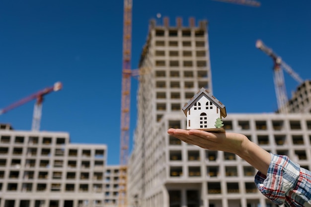 Foto uma mão de mulher segura uma maquete contra o fundo de um prédio de apartamentos