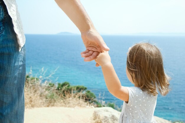 Uma mão de pais e filhos felizes no mar em fundo de viagem na Grécia