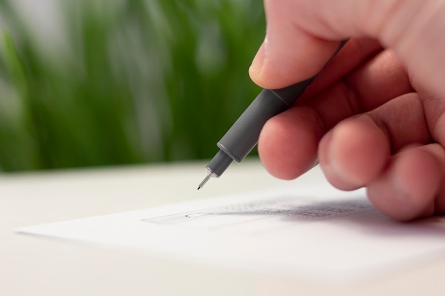 Uma mão desenha com um forro de caneta em um pedaço de papel