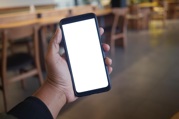 Uma mão está segurando um smartphone enquanto está sentado em um ambiente de café moderno