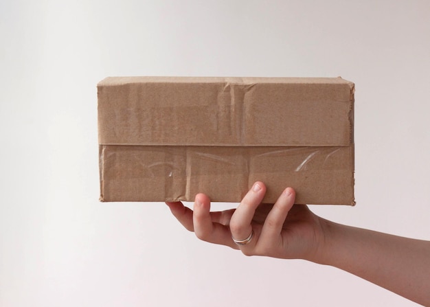 Foto uma mão estende um pacote, uma caixa de papelão amassada