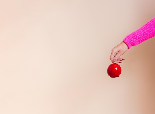 Uma mão feminina segurando a maçã do amor.