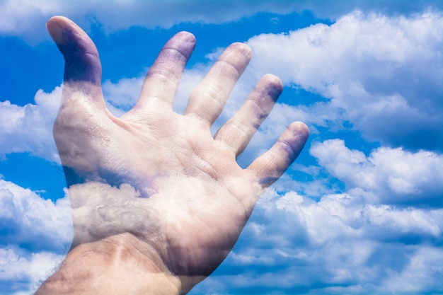 Uma mão humana e o céu azul.