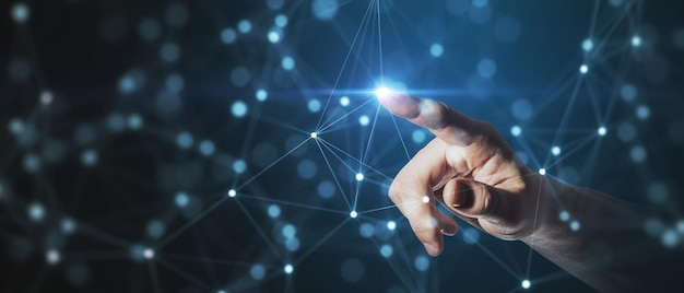 Uma mão humana estendendo-se para tocar um ponto dentro de uma complexa rede de conexões simbolizando interação e alcance tecnológico