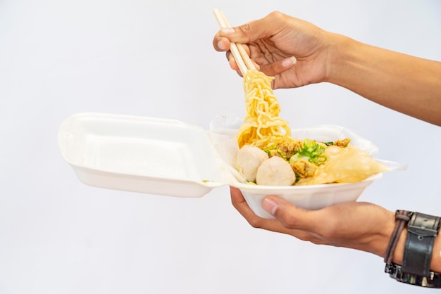 Uma mão humana segurando macarrão de frango mie ayam com fundo branco Comida tradicional da Indonésia