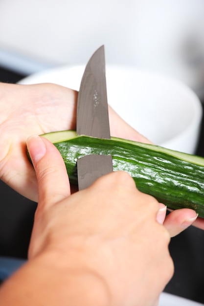 uma mão masculina descascando um pepino na cozinha