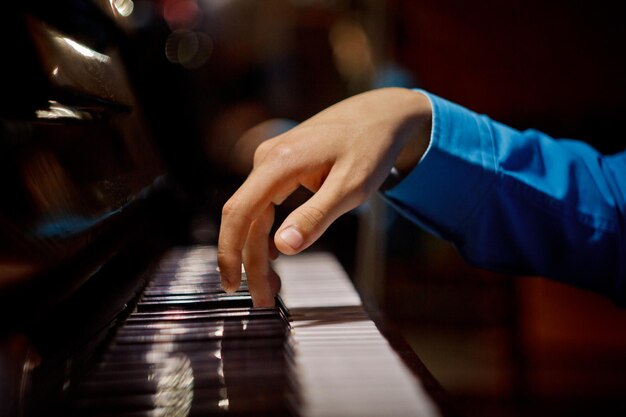 Foto uma mão masculina no piano a palma da mão está sobre as teclas e toca o instrumento de teclado na escola de música aluno aprende a tocar mãos pianista preto fundo escuro