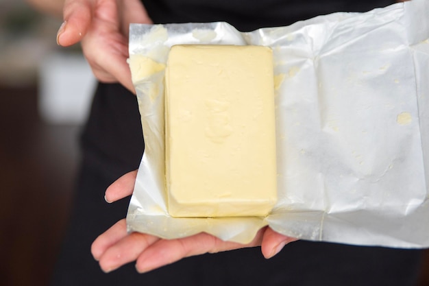 Uma mão segura manteiga em um processo de close-up de fazer sanduíches com manteiga