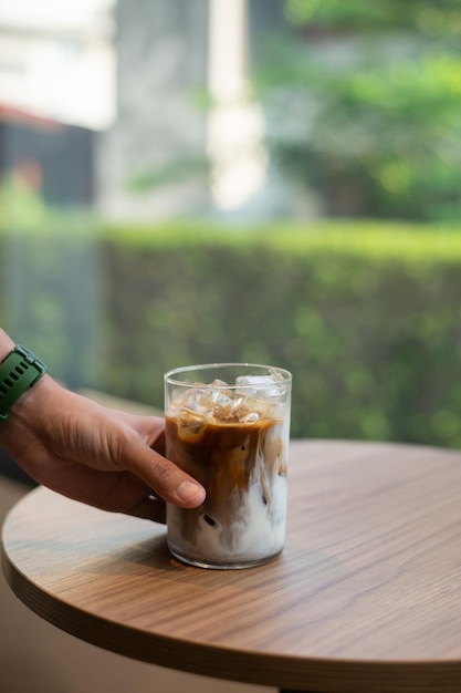 Uma mão segura um copo de café gelado