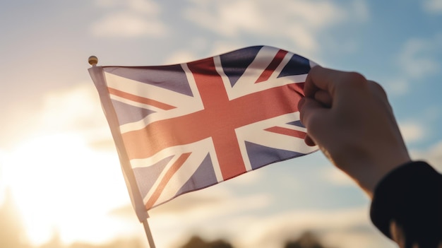Uma mão segura uma bandeira britânica na frente de um pôr do sol