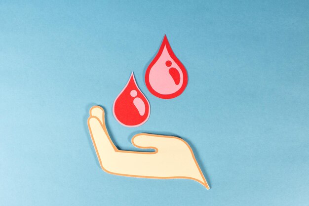 Foto uma mão segurando duas gotas vermelhas de sangue conceito de doação de sangue
