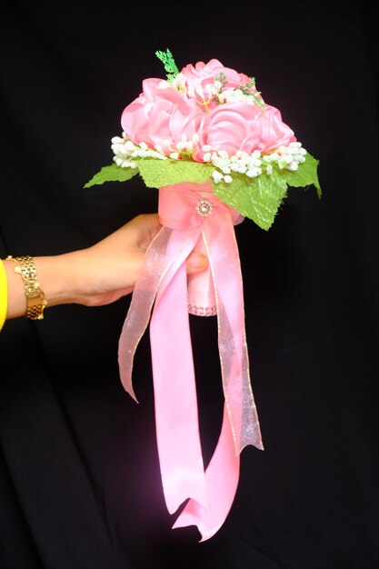 uma mão segurando um buquê de flores feito de fitas e tecido de cetim. buquê de noiva chique romântico.